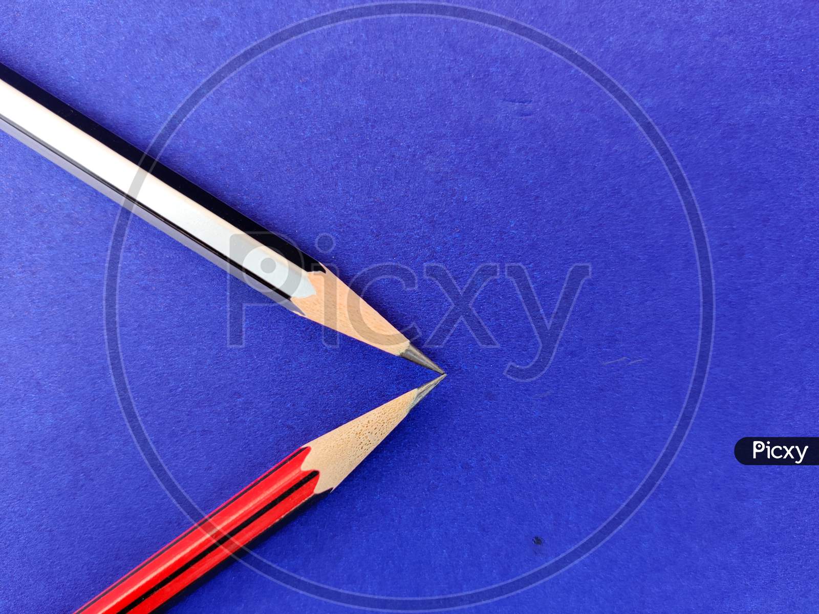 Copy Space Of Red And Black Color Pencil Pointing Each Other On Blue Background