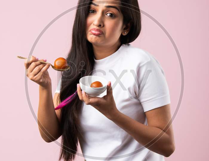 Indian Asian Pretty Young Woman Eating Gulab Jamun Sweet Food With Spoon