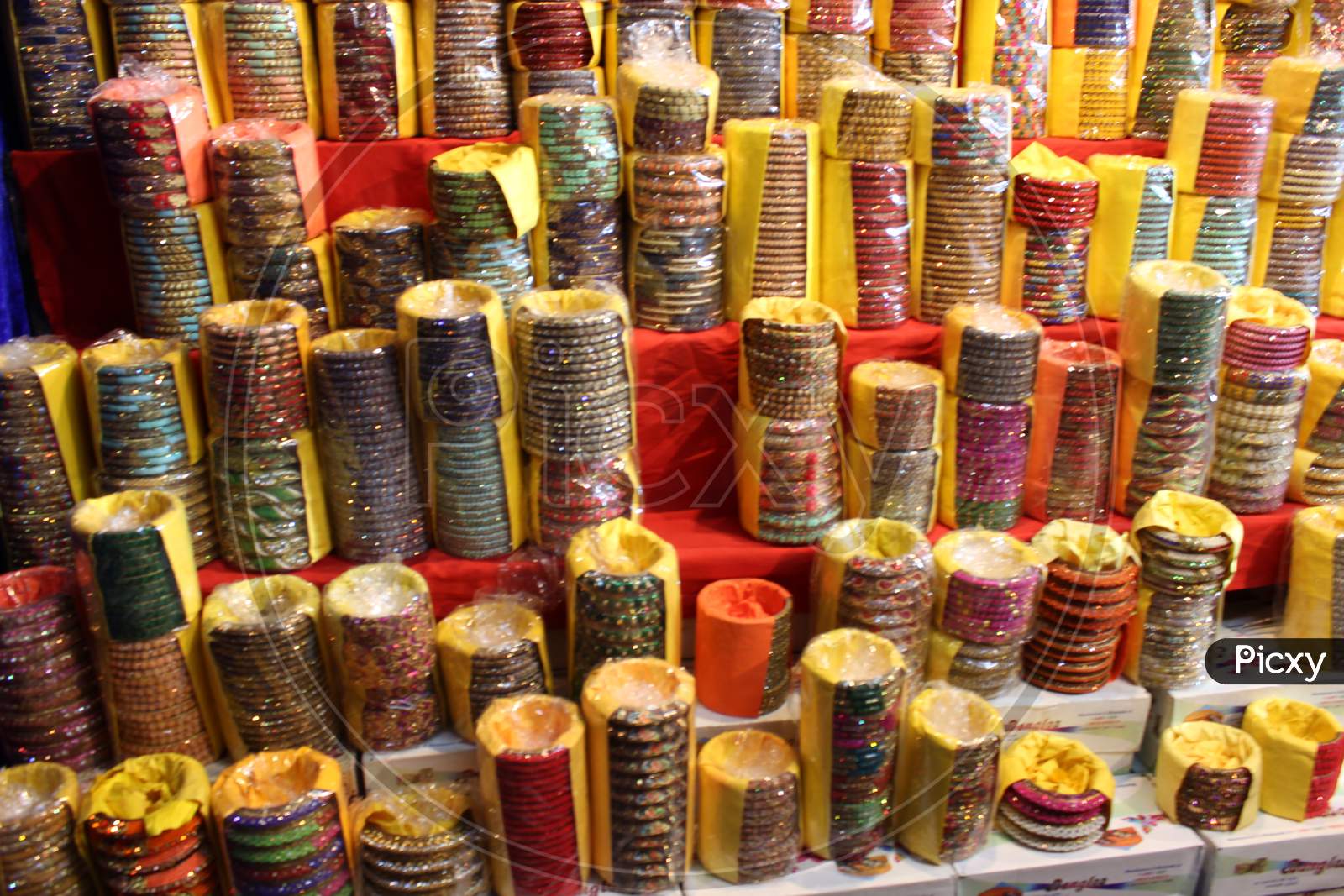 Background Of Colorful Bangles Stacked In A Shop In India With Glitter And Plain Colored Bangles. The Bangles Are Made Of Glass, Metal Or Lac And Worn Regularly Or On Special Occasions By Indian Women