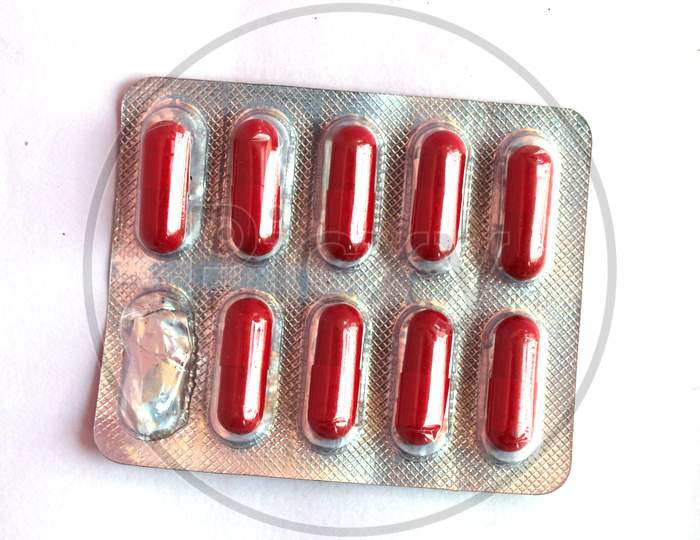 Blister Pack With Pharmaceutical Drug In The Form Of Red Capsules With One Used Capsule On A Light Colored Table, Top View