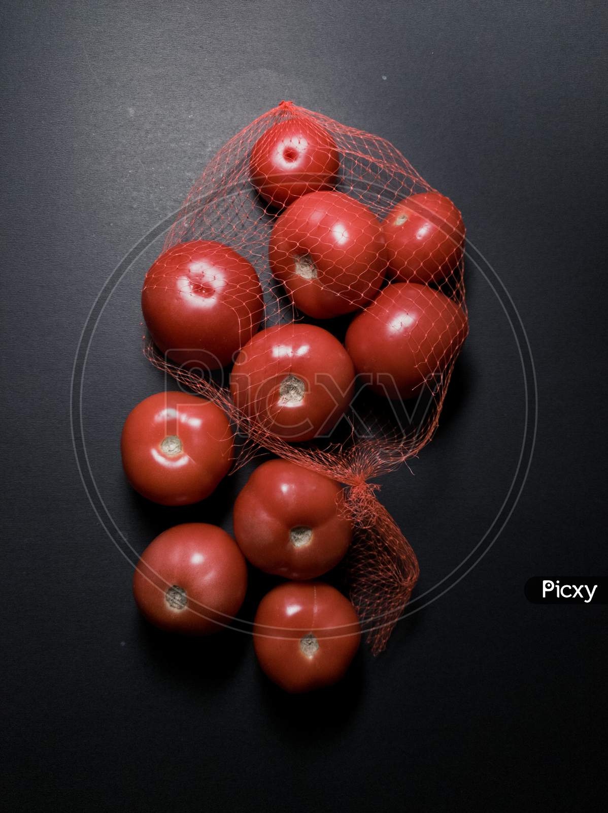 Red tomatoes in dark and moody background
