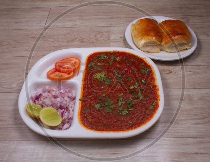 Pav Bhaji Is A Fast Food Dish From India, Thick And Spicy Vegetable Curry, Fried And Served With A Soft Bread Roll / Bun Paav And Butter. Served On A Colorful Or Wooden Background. Selective Focus