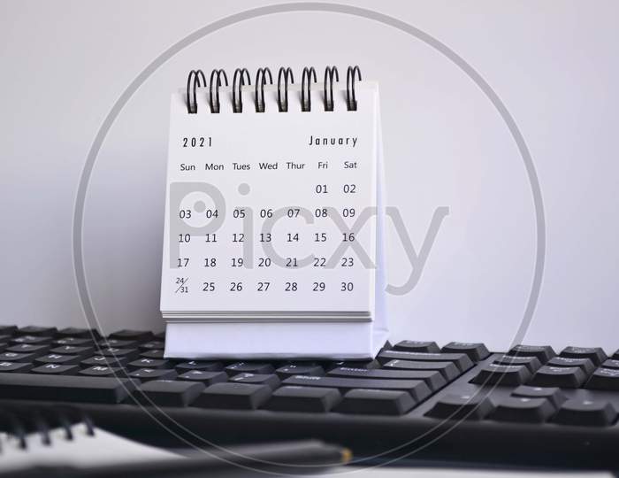 White January 2021 Calendar On A Blurred Keyboard, Pen And Notebook With White Backgrounds. New Year Concept