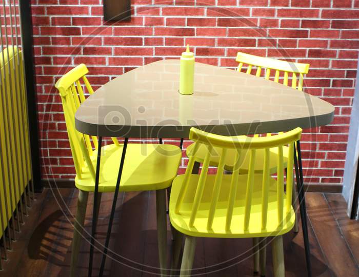 Empty Table And Yellow Chair In Room With Red Wall
