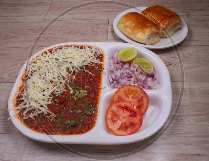 Cheese Pav Bhaji Is A Fast Food Dish From India, Thick And Spicy Vegetable Curry, Fried And Served With A Soft Bread Roll / Bun Paav And Butter. Served On A Colorful Or Wooden Background. Selective Focus