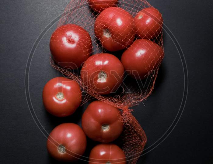 Red tomatoes in dark and moody background