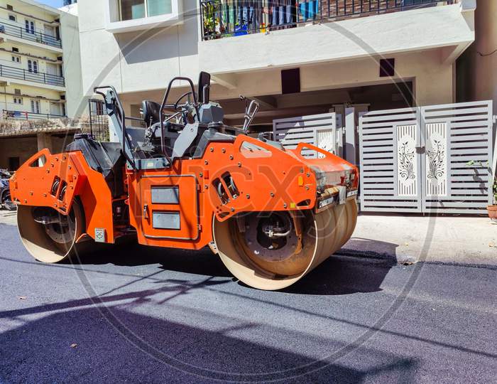Stock Photo Of A Orange Color Road Roller Parked On The Newly Constructed Damber Road For Rolling Black Topping For Renovation Of Road At Bangalore City Karnataka India.
