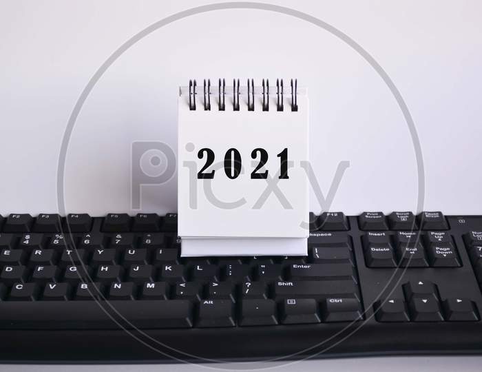 2021 text on white stand paper on a blurred keyboard with white backgrounds. New Year Concept