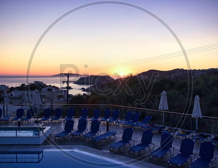 Crete, Greece - September 11, 2017: A Back Of A Random Hotel Property And Bunch Of Tanning Ledge By The Swimming Pool Against Sunset Or Sunrise In A Famous Greek Island