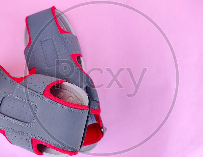 Top View Of Grey And Red Color Pair Of Men Sandals Or Slipper Isolated On Pink Background
