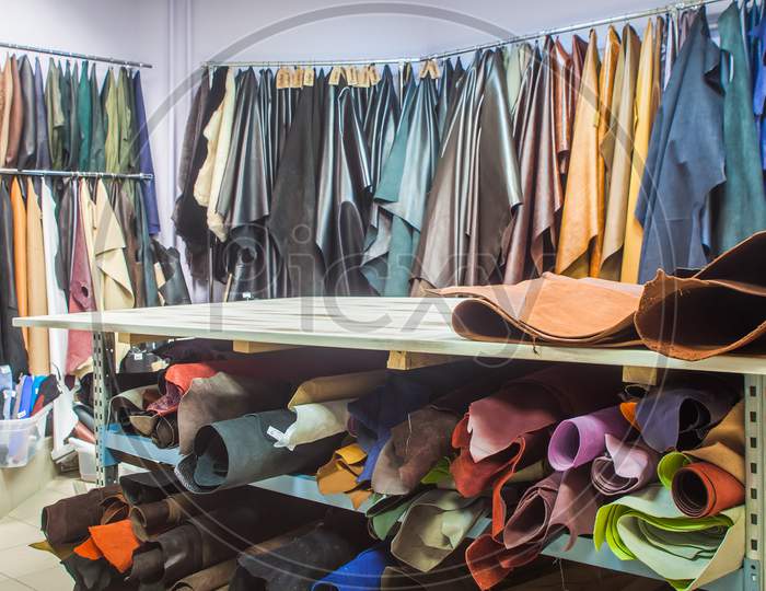 Furrier'S Working Table For Cutting, On An Abstract Background, Pieces Of Natural And Artificial Leather Hang In Several Rows Of Different Colors: Brown, Blue, Green, Red, Black, White, And Others.