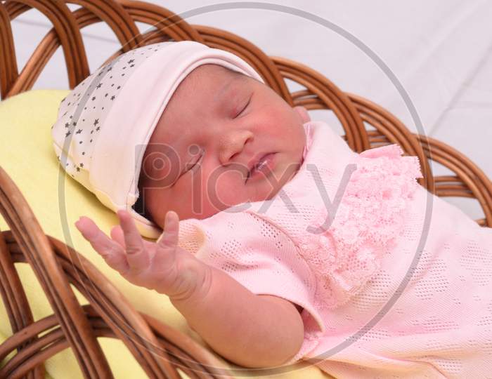 Portrait Of Newborn Baby Sleeping In Basket With Pink Towel Isolated Over White Background