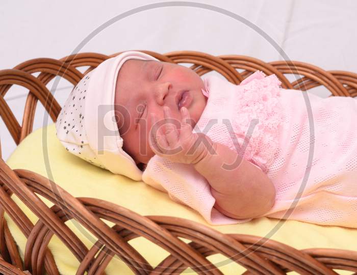 Portrait Of Newborn Baby Sleeping In Basket With Pink Towel Isolated Over White Background