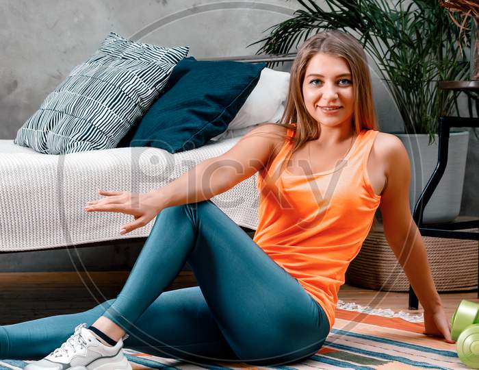 The Young Woman Goes In For Sports At Home. Cheerful Sporty Woman With Blond Hair Makes Press   In The Bedroom