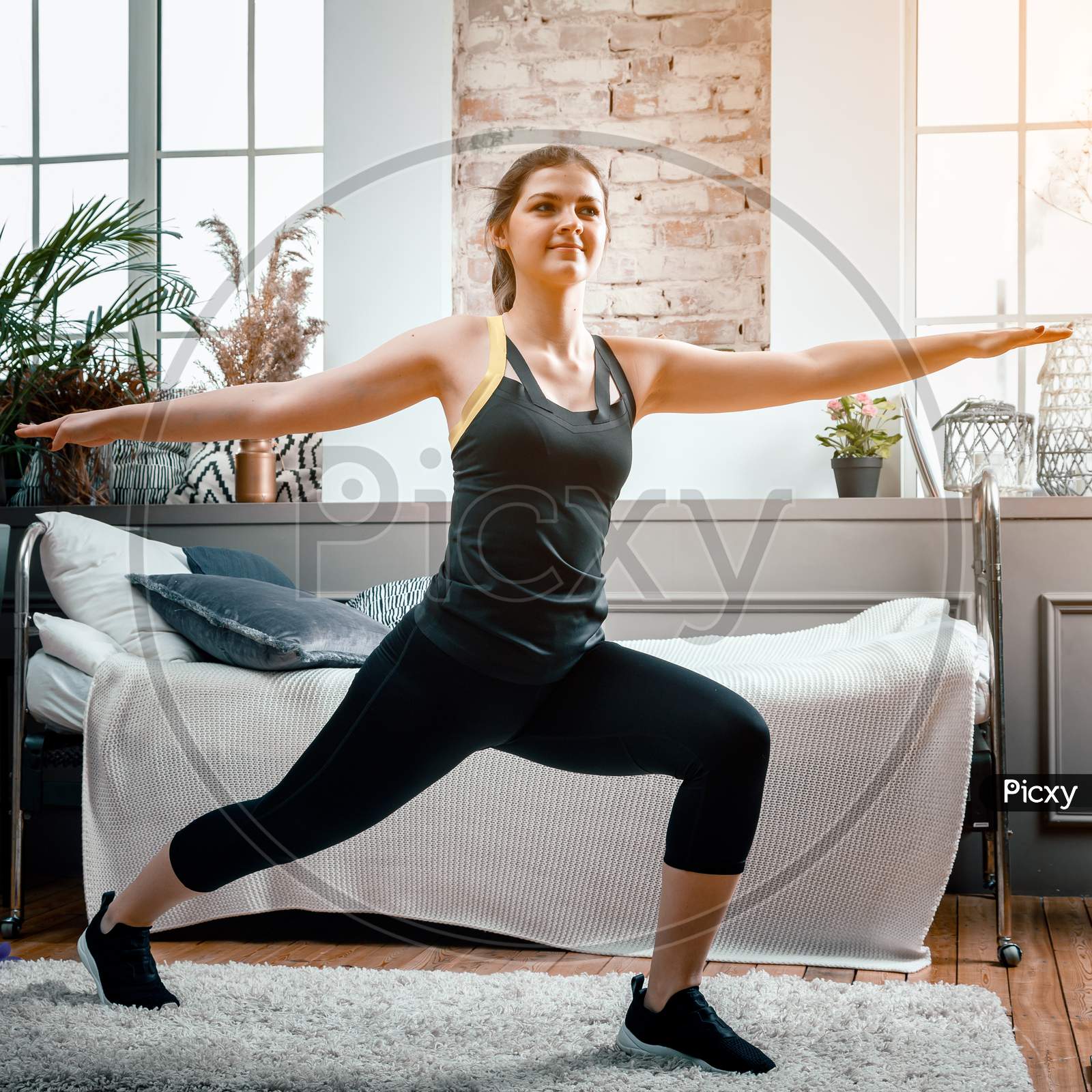 A Young Woman Goes In For Sports At Home, Online Workout From The Laptop. The Athlete Lunges   In The Bedroom, In The Background There Is A Bed, A Vase, A Carpet.