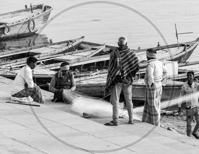 Fisherman repairing fish net.