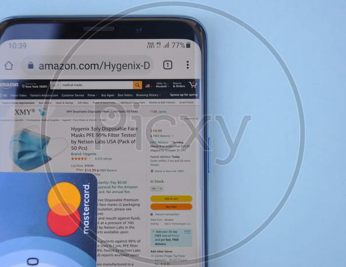 Mandi, Himachal Pradesh, India - 03 04 2021: High angle of buying medical mask online with Mastercard, Amazon website on smartphone which is a world's top international electronic commerce company