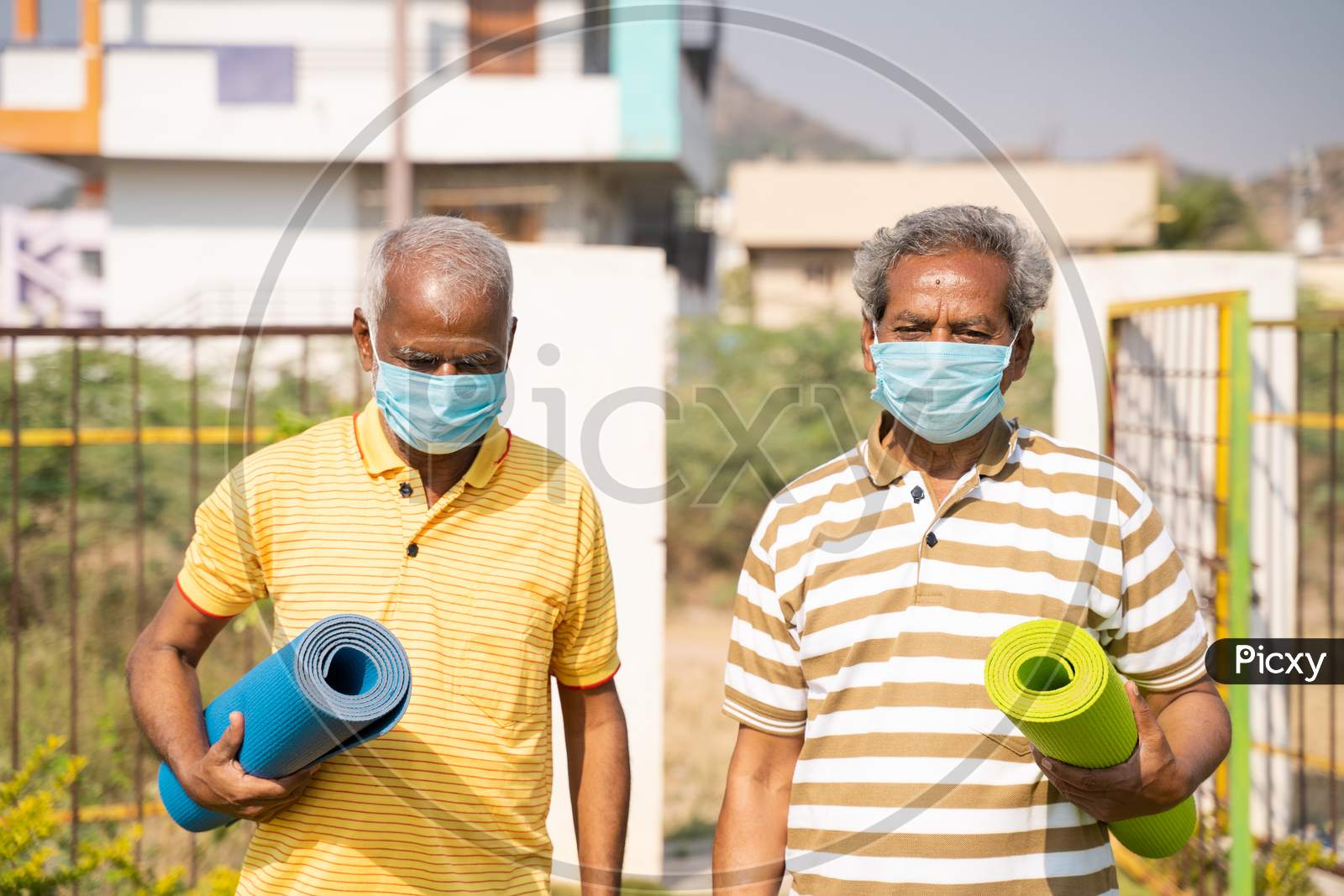 Two Senior People With Yoga Mat And Medical Face Mask In Park - Healthy Elderly Men With Fitness Mat Coming For Yoga During Coronavirus Covid-19 Pandemic