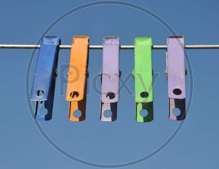 Front view of colorful cloth clips hanging on wire with blue sky in background