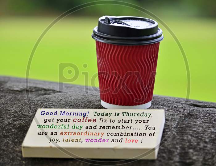 Red Paper Cup Of Coffee With Text Written On Chalkboard And Greenery Background