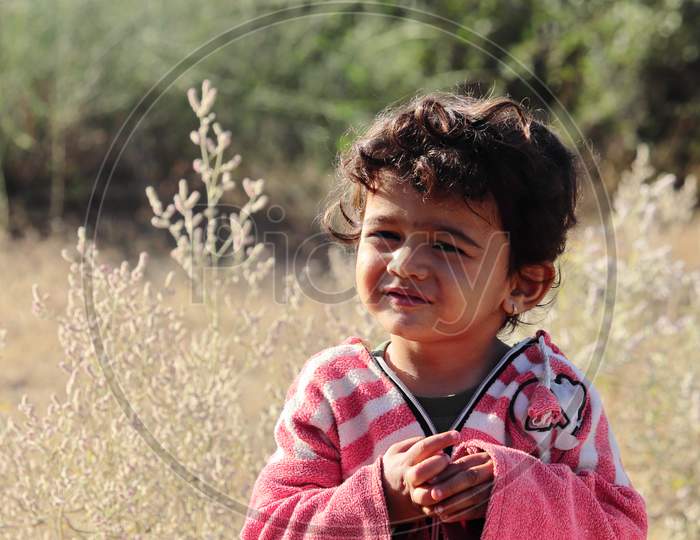 A Small Boy Of Indian Origin Looking At The Camera With Small Eyes