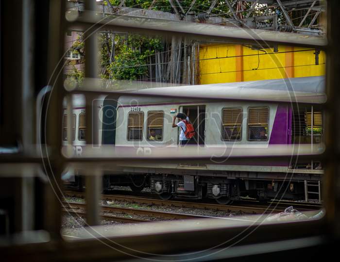 Unidentified Passengers Standing On The Doors Of Running Local Train During Rush Hours