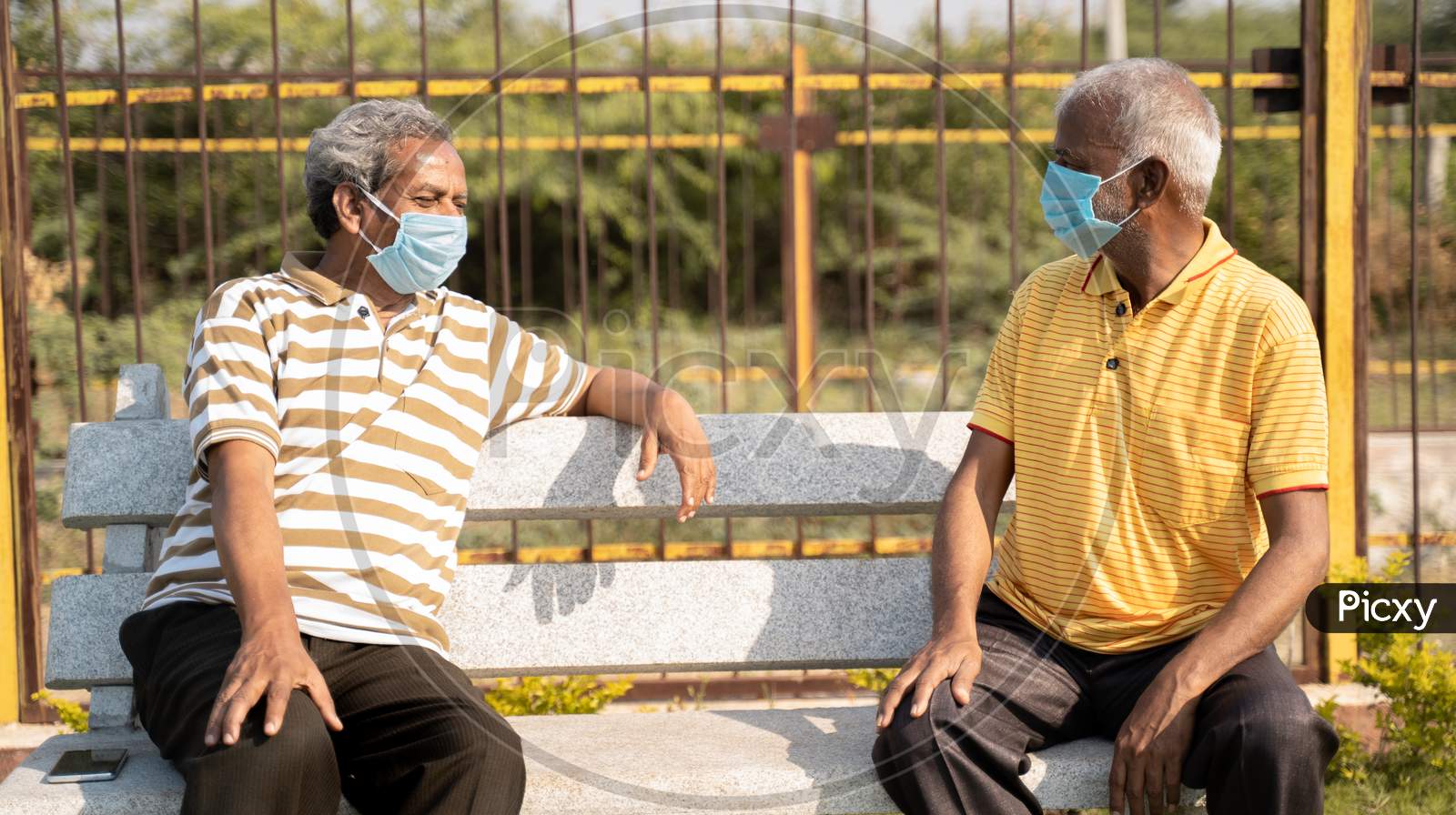 Two Old Senior Friends With Medical Mask Spending Good Time By Talking And While Maintaining Social Distancing At Park - Concept Of New Normal Lifestyle Due To Coronavirus Covid-19 Pandemic