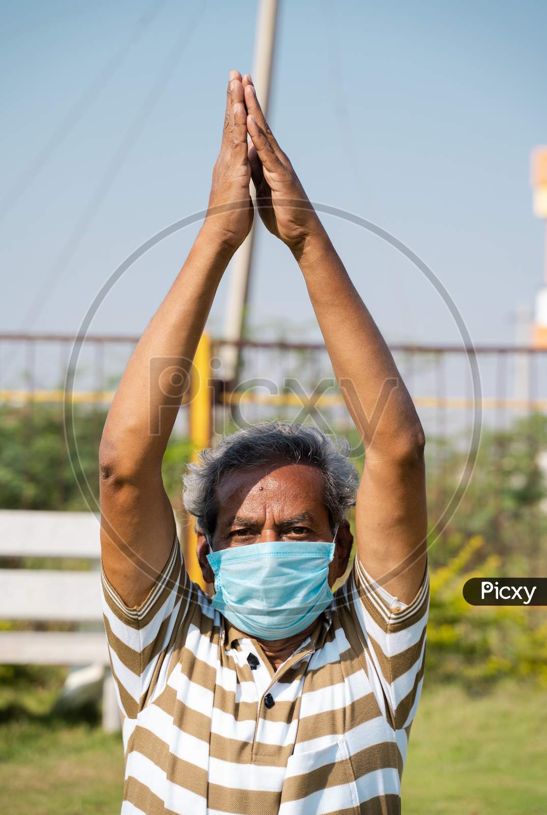 Old Man With Medical Face Mask Busy Doing Surya Namaskara Yoga Or Exercise During Morning - Concept Of Senior People Fitness Workout And Healthcare During Coronavirus Coivd-19 Pandemic