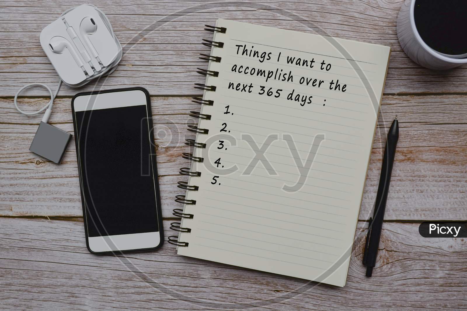 Text On Notepad With Cup Of Coffee, Smart Phone, Music Player And Pen On Wooden Desk
