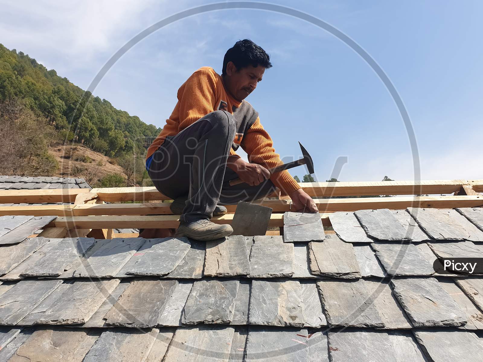 Process of construction work of rooftop, Construction worker laying slate roof tiles on the roof of an Indian building with selective focus, selective focus on subject, background blur