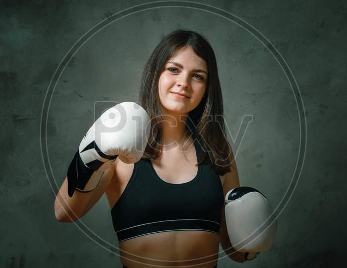 Young  Angry Fighter Girl With White Gloves Fighting Practice Throwing Aggressive Punch Training Shadow Boxing Workout  On Black Dirty Grunge Background