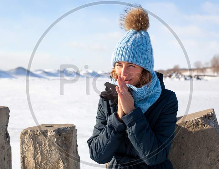 Fashion Lifestyle Portrait Of Young Trendy Woman Dressed In Warm Stylish Clothes   Warm Hands And Froze Up In The  Winter.  Portrait Of Joyful Woman, In The Background White Snow And Frozen Mountains