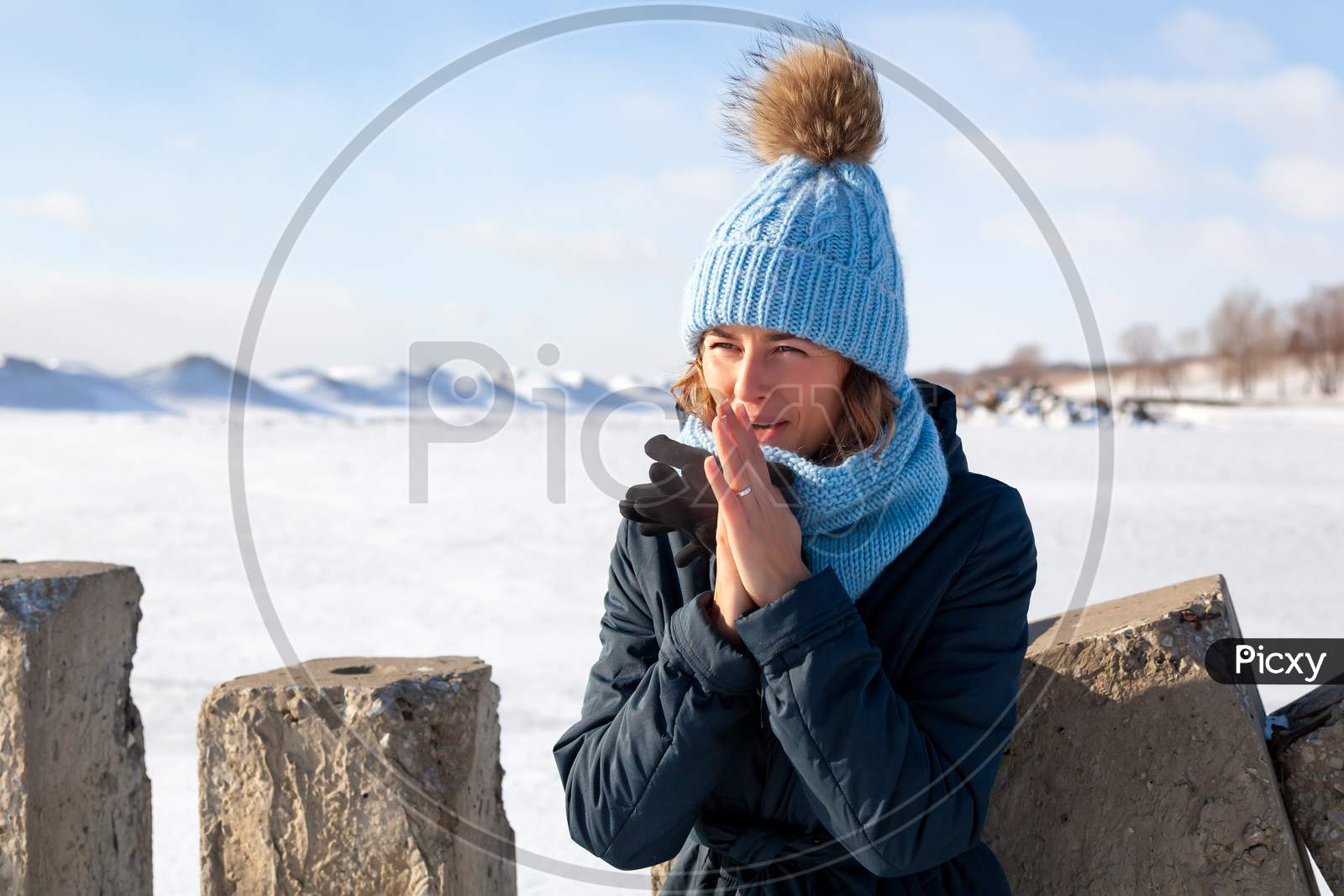 Fashion Lifestyle Portrait Of Young Trendy Woman Dressed In Warm Stylish Clothes   Warm Hands And Froze Up In The  Winter.  Portrait Of Joyful Woman, In The Background White Snow And Frozen Mountains