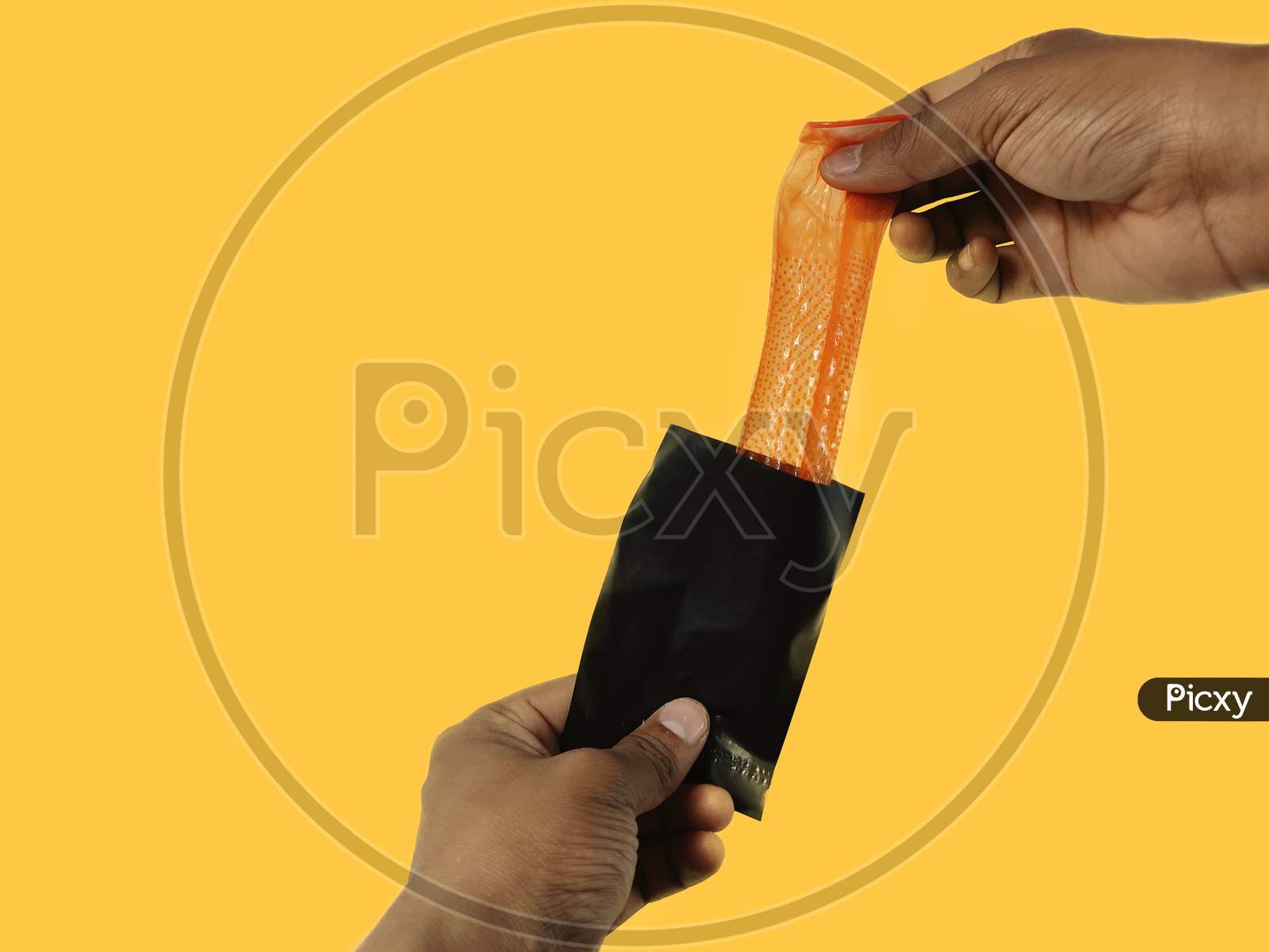 Image of Man hand holding Condom placing inside disposable packet sachet  through after sex disposal practice yellow background with copy  space-EY221316-Picxy