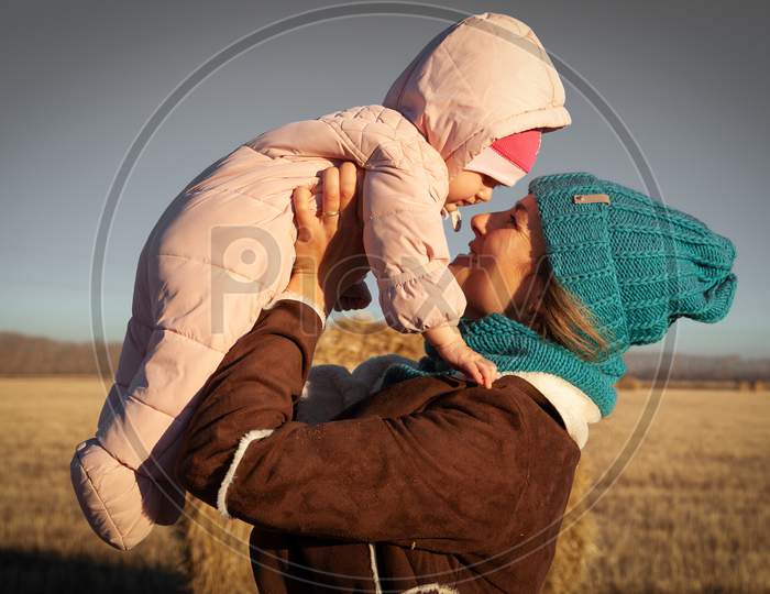 The Concept Of Livestyle  Outdoor In Autumn. Close Up Of A Young Woman Student In A Warm Autumn Clothes With Baby Looking Funny, Smilling, Posing And Playing With Daughter  On The  Field Stack