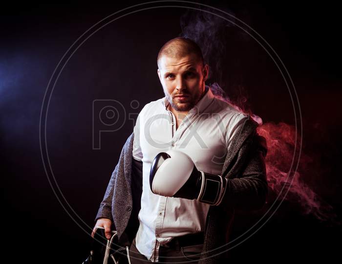 Young Handsome Man Businessman In White Shirt, Gray Suit, White And Black Gloves  Took Off His Jacket And Looked Inquiringly  Against Red  And Blue Smoke From A Vape  On Black Isolated
