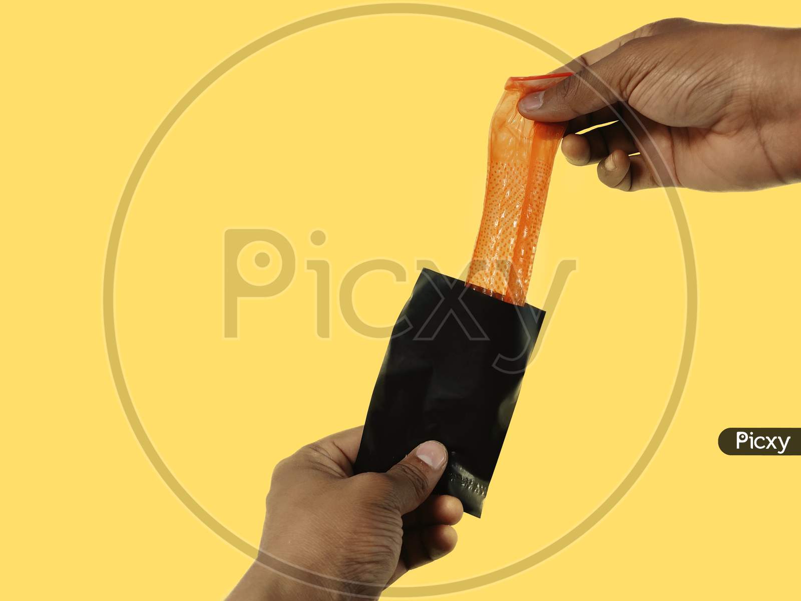 Image of Man hand holding Condom placing inside disposable packet sachet  through after sex disposal practice yellow background with copy  space-ON323714-Picxy