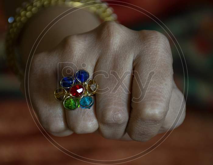 Stock Photo Of A Indian Girl Wearing Combination Of Red ,Blue, Green ,Gold Color Stone Ring, In Her Ring Finger On Blur Background At Bangalore City Karnataka India.
