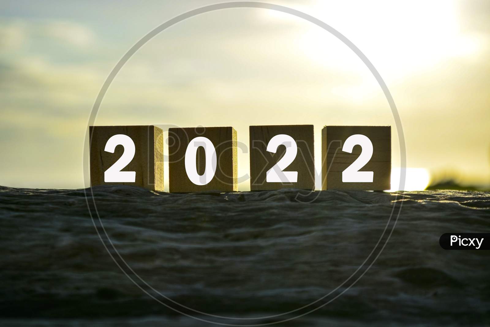 2022 Number On Wooden Cube Block On Old Tree Stump With Blurred Background Of Green Grass Ocean And Sunset