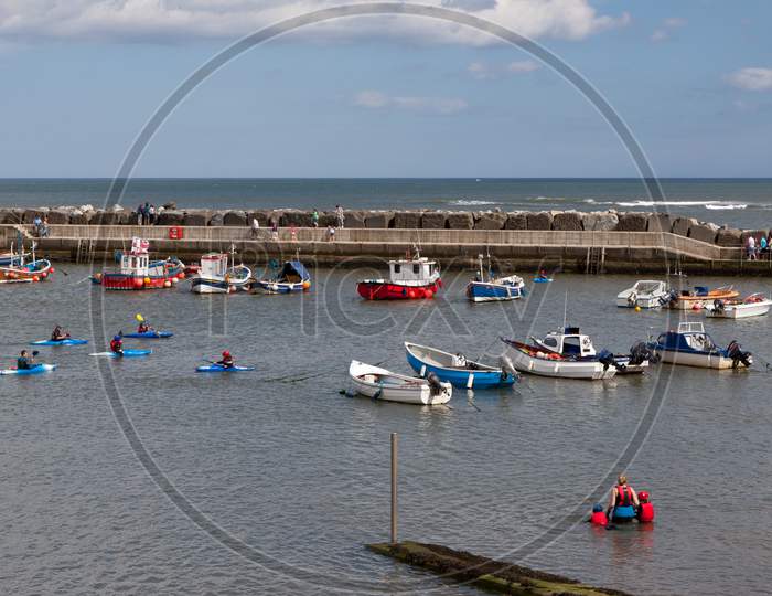 People Enjoying Themselves In Staithes Harbour North Yorkshire