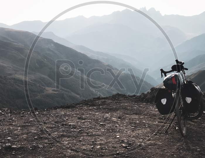 Loaded Touring Bicycle Stands With Moody Dramatic Panoramic Mountains View And No Cyclist