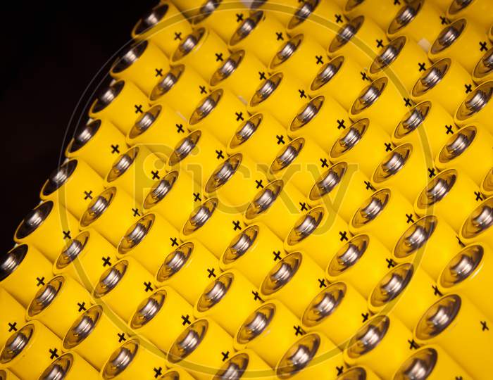 Alkaline Battery Aa Size. Several Batteries In Rows.A Close-Up Of The Same Yellow Batteries, Lined Up In Even Rows By Positive Charges. An Unsafe Way To Use Energy.