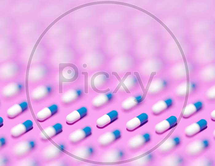 3D Illustration White -  Blue  Capsules, Tablets With Medicine In Even Rows On A Pink  Background. Capsule Medicine