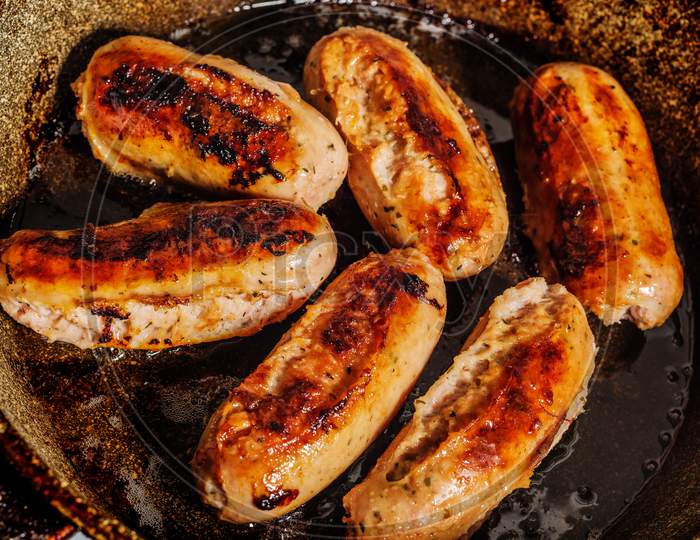 Six burnt fried German hunting sausages in a burnt frying pan