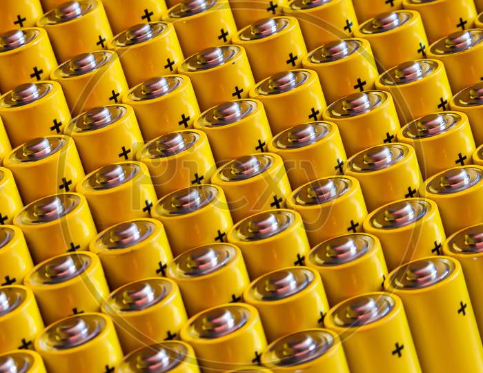 Alkaline Battery Aa Size. Several Batteries In Rows.A Close-Up Of The Same Yellow Batteries, Lined Up In Even Rows By Positive Charges. An Unsafe Way To Use Energy.