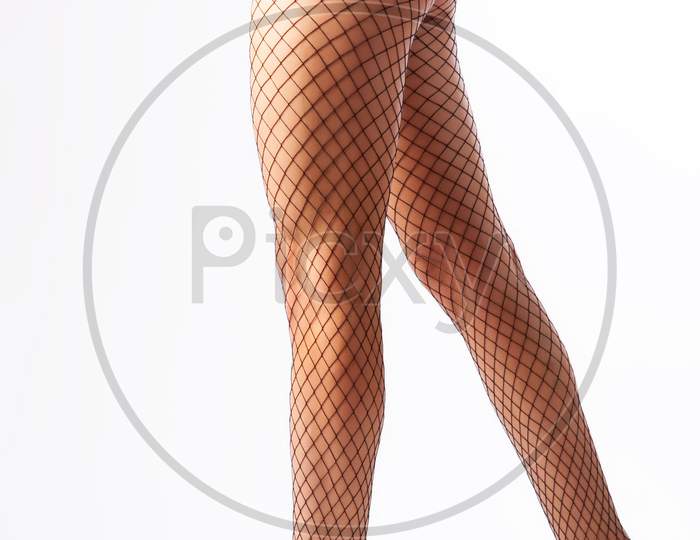 Close-Up Of Beautiful Woman'S Slim Legs In Nylon Black Tights In A Mesh Posing In An Elegant Pose On White Isolated Background. Concept Of Beauty Woman Posing For Legs. Woman In Hosiery.