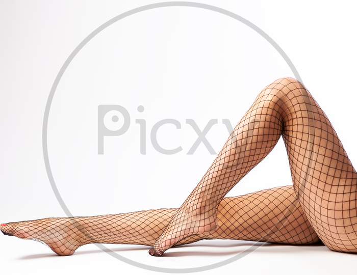 Close-Up Of Beautiful Woman'S Slim Legs In Nylon Black Tights In A Mesh Posing In An Elegant Pose On White Isolated Background. Concept Of Beauty Woman Posing For Legs. Woman In Hosiery.