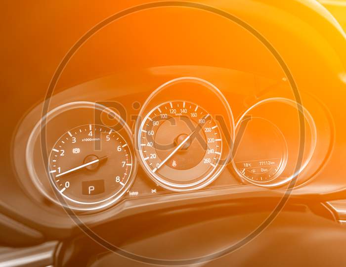New Car Interior Details. Speedometer, Tachometer And Steering Wheel Under The Yellow And Orange Neon Color