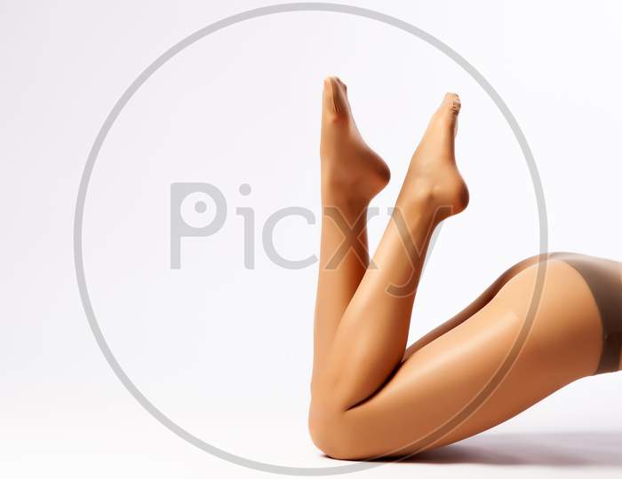 Close-Up Of Beautiful Woman'S Slim Legs In Flesh-Colored Nylon Pantyhose Posing In An Elegant Pose On A White Isolated Background. Concept Of A Woman'S Beauty, Legs. Woman In Hosiery.