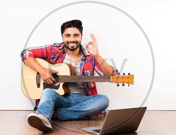 Indian Asian Young Man Playing Guitar With Laptop, Learning Or Recording Video